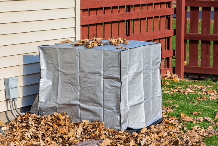 covered ac unit with leaves surrounding it